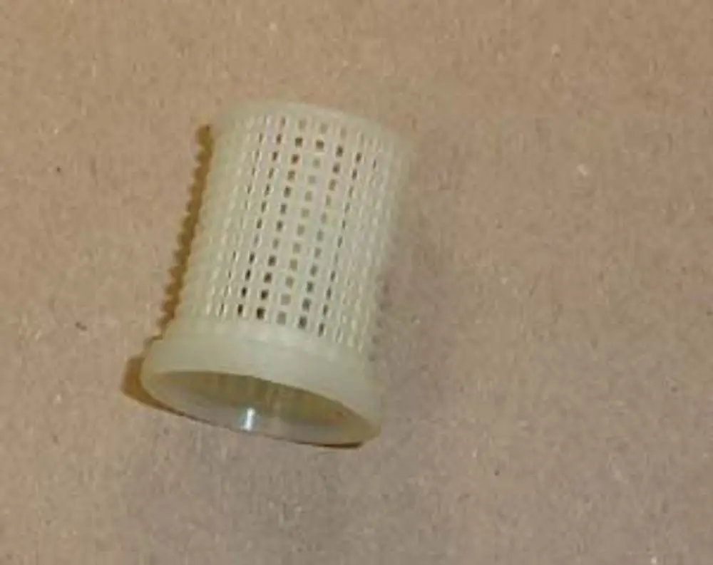 Vorlauf Filter, hergestellt von Remeha, aus transparentem Material mit einem körnigem Muster, liegend auf einer einfarbigen Fläche.